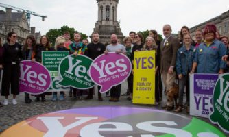 Amnesty International Irlandia w Dublinie, akcja na zewnątrz, grupa aktywistów_aktywistek stoi z banerami za powiedzeniem tak w referendum, które mzadecydowało o usunięciu z konstytucji kraju określenia ochrony życia od począcia.