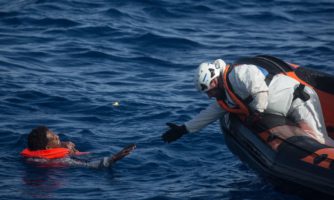 Członek załogi ratowniczej MOAS (Migrant Offshore Aid Station) próbuje ratować mężczyznę, maj 2018.