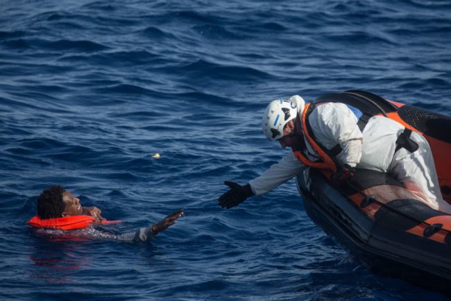 Członek załogi ratowniczej MOAS (Migrant Offshore Aid Station) próbuje ratować mężczyznę, maj 2018.