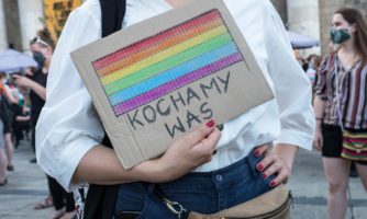 Protest solidarnościowy z osobami LGBTI+ oraz aktywistami_kami, których spotkały represje 7 sierpnia 2020, podczas tzw. tęczowej nocy. Osoba na zdjęciu trzyma karton z namalowanymi tęczowymi barwami i z napisem "kochamy was".