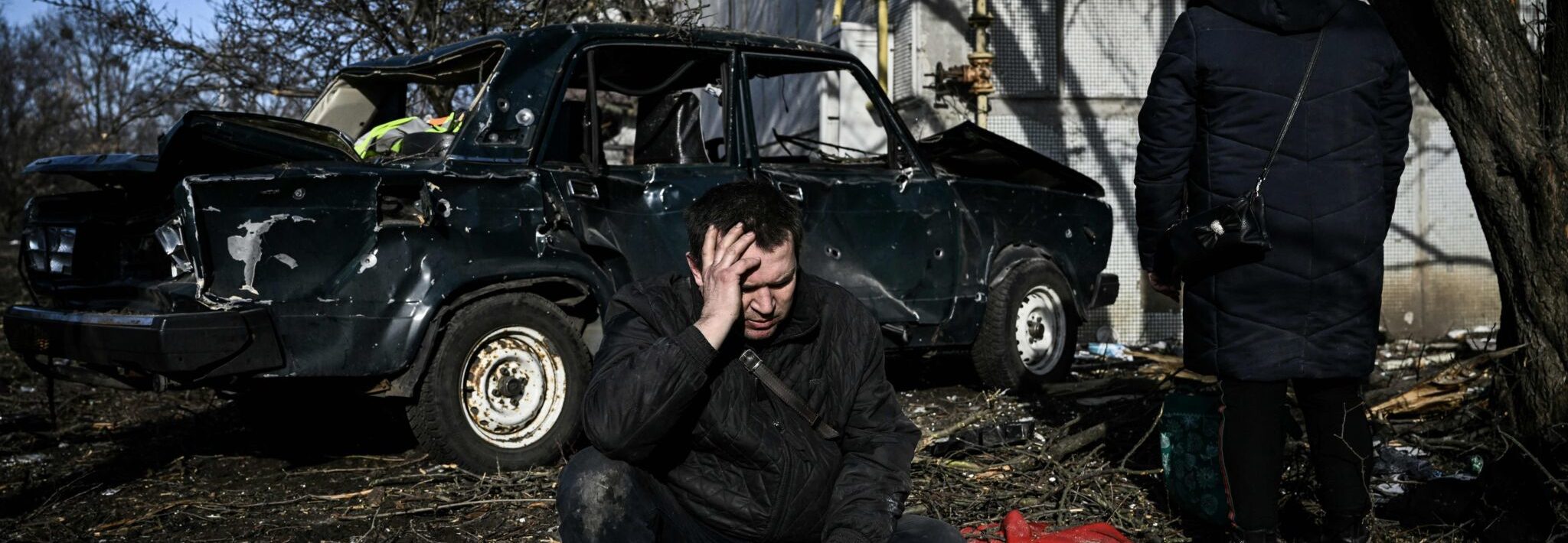 A man sits outside his destroyed building after airstrikes on the Eastern Ukraine town of Chuguiv on February 24, 2022. Photo by ARIS MESSINIS/AFP via Getty Images)