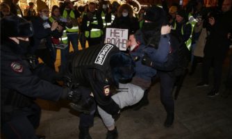 Police officers detain a man holding a placard reading "No war" during a protest at Pushkinskaya Square on February 24, 2022 in Moscow, Russia. (Photo by Konstantin Zavrazhin/Getty Images)