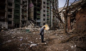 A man stands in front of a residential building damaged in yesterday's shelling in the city of Chernihiv on March 4, 2022. Photo by DIMITAR DILKOFF/AFP via Getty Images