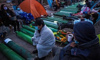 People camp as they wait to refill empty oxygen cylinders in Villa El Salvador, on the southern outskirts of Lima, on February 25, 2021, amid the COVID-19 coronavirus pandemic. Photo by ERNESTO BENAVIDES / AFP