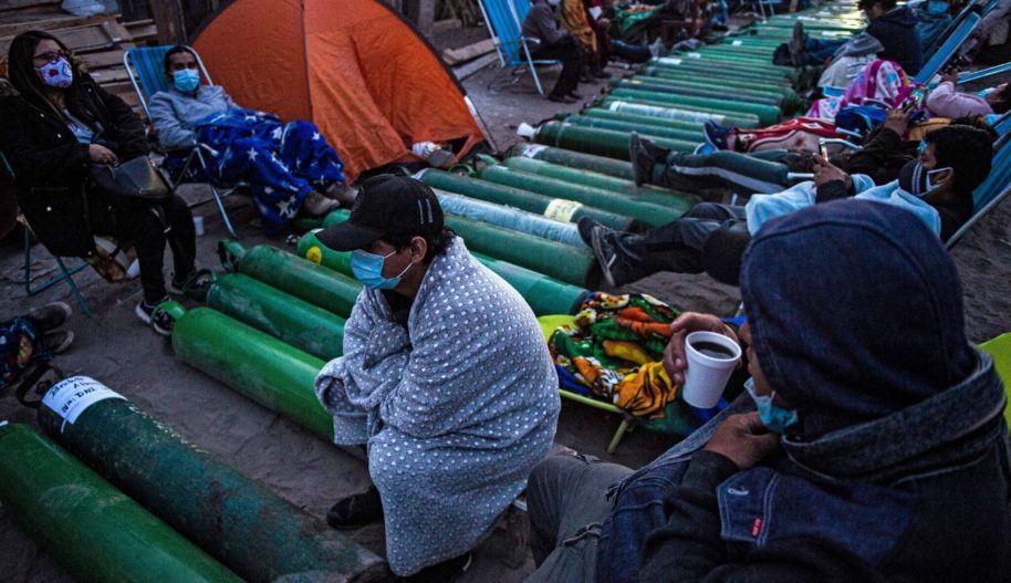 People camp as they wait to refill empty oxygen cylinders in Villa El Salvador, on the southern outskirts of Lima, on February 25, 2021, amid the COVID-19 coronavirus pandemic. Photo by ERNESTO BENAVIDES / AFP