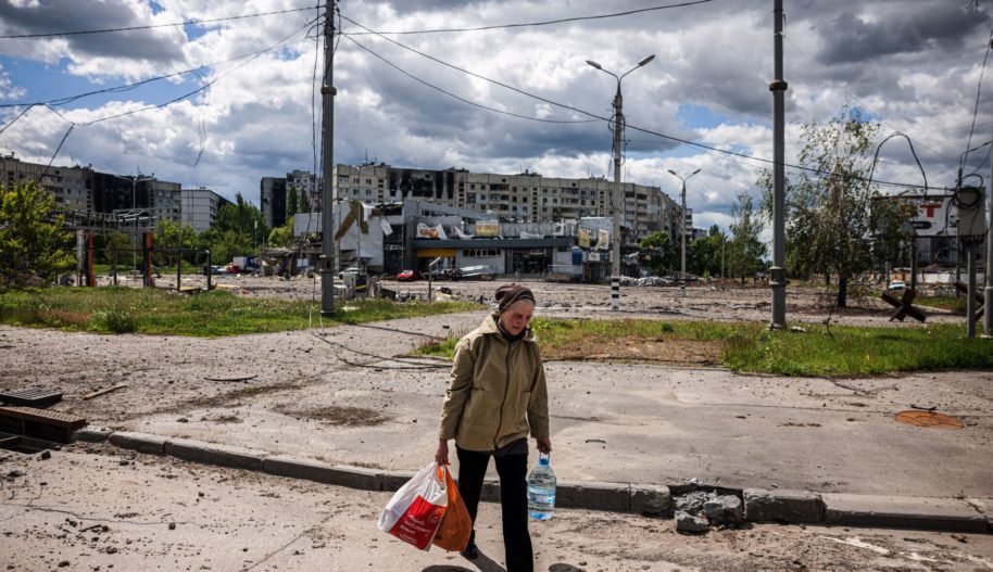 Kobieta niesie torby z jedzeniem podczas spaceru w dzielnicy Saltiwka, północny Charków, 17 maja 2022 r. (Photo by Dimitar DILKOFF / AFP) (Photo by DIMITAR DILKOFF/AFP via Getty Images)