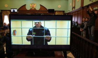 Rosyjski polityk opozycyjny, działacz antykorupcyjny i założyciel Fundacji Antykorupcyjnej (FBK), Aleksiej Nawalny jest widziany na ekranie podczas apelacji prawnej od wyroku dziewięciu lat więzienia, w Moskiewskim Sądzie Miejskim, 24 maja 2022 roku.