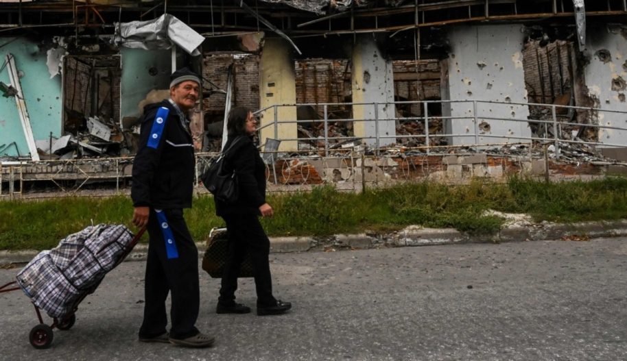 Zdjęcie zrobione 11 września 2022 roku pokazuje parę z walizkami, która spaceruje przed zniszczonym budynkiem w Izium, w obwodzie charkowskim, na wschodzie Ukrainy, w czasie rosyjskiej inwazji na Ukrainę. - Siły ukraińskie powiedziały, że ich błyskawiczna kontrofensywa odebrała więcej ziemi w ciągu ostatnich 24 godzin, ponieważ Rosja odpowiedziała uderzeniami na niektóre z odzyskanych terenów. Zmiany terytorialne były jednym z największych odwrotów Rosji od czasu, gdy jej siły zostały zawrócone z Kijowa w pierwszych dniach prawie siedmiomiesięcznych walk, ale Moskwa zasygnalizowała, że nie jest bliżej uzgodnienia wynegocjowanego pokoju.