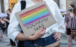Protest solidarnościowy z osobami LGBTI+ oraz aktywistami_kami, których spotkały represje 7 sierpnia 2020, podczas tzw. tęczowej nocy. Osoba na zdjęciu trzyma karton z namalowanymi tęczowymi barwami i z napisem "kochamy was".