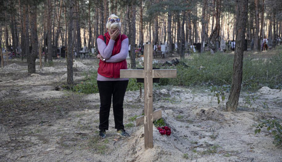 Ukrainka opłakuje zmarłego męża przy krzyżu w lesie pod miastem Izium, gdzie znaleziono miejsce masowego pochówku osób, które zginęły w skutek rosyjskiego oblężenia. 19 września 2022. Photo by Metin Aktas/Anadolu Agency via Getty Images