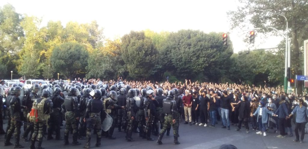 Grupa uzbrojonych funkcjonariuszy służb bezpieczeństwa naprzeciw pokojowo protestujących w Teheranie