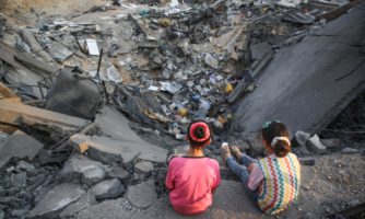 Dwójka dzieci siedząca na krawędzi krateru po bombardowaniu.