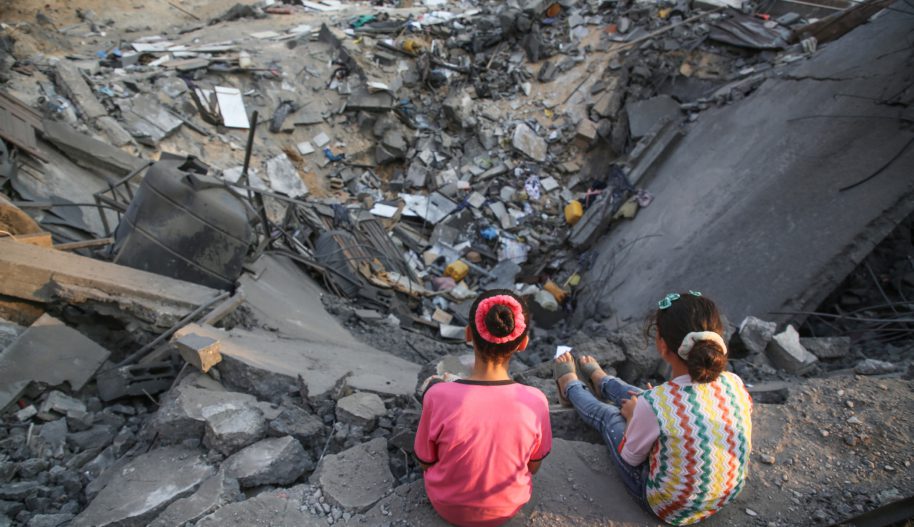 Dwójka dzieci siedząca na krawędzi krateru po bombardowaniu.