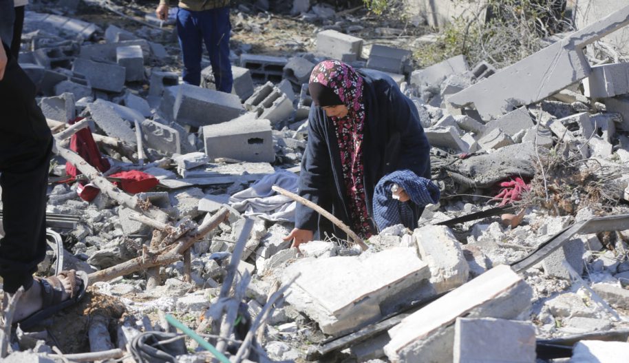 Zdjęcie kobiety szukającej bliskich w gruzach po bombardowaniu obozu dla uchodźców w Strefie Gazy.