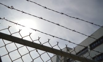 Zdjęcie drutów kolczastych w ogrodzeniu więzienia na tle nieba.