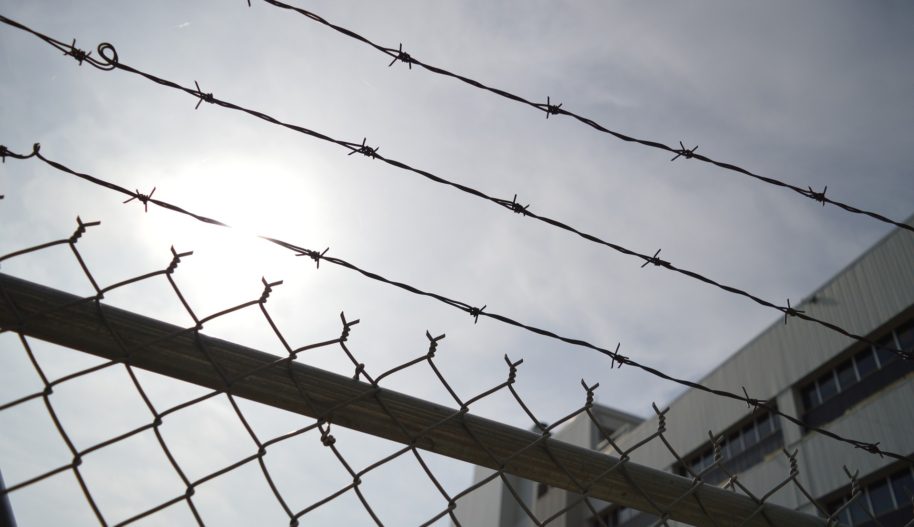 Zdjęcie drutów kolczastych w ogrodzeniu więzienia na tle nieba.