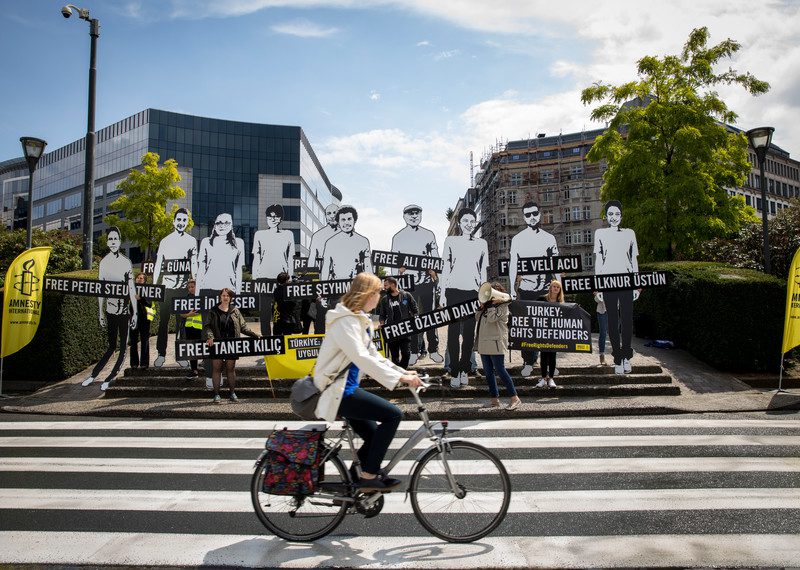 Aktywiści protestują przed budynkiem Komisji Europejskiej w Brukseli, aby pilnie podnieść świadomość na temat uwięzionych obrońców praw człowieka - w tym dyrektorki i przewodniczącej Amnesty International w Turcji, Idil Eser i Taner Kılıç.