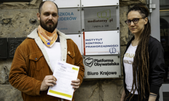 Dwie osoby trzymają tekst petycji przed Biurem Platformy Obywatelskiej w Warszawie.