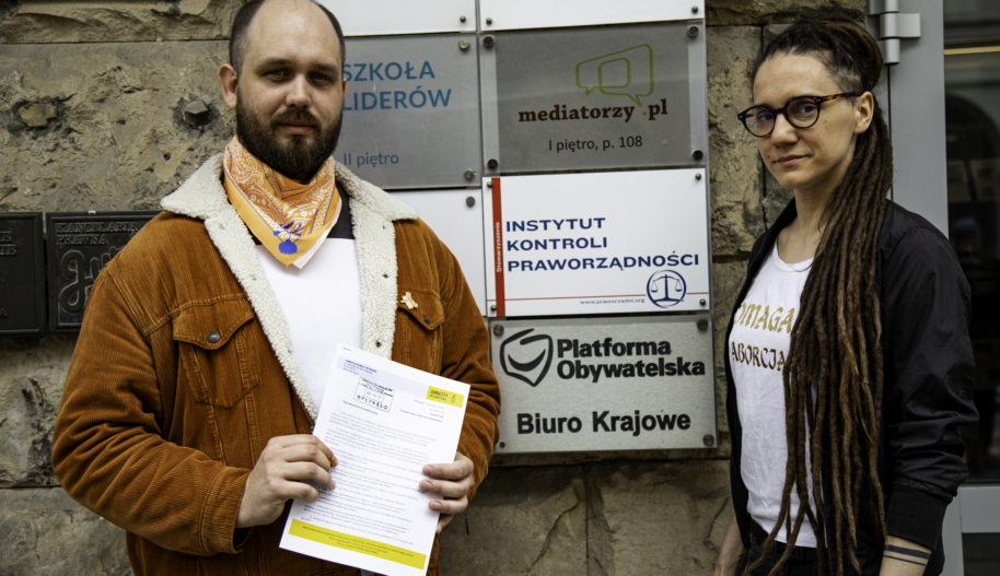 Dwie osoby trzymają tekst petycji przed Biurem Platformy Obywatelskiej w Warszawie.