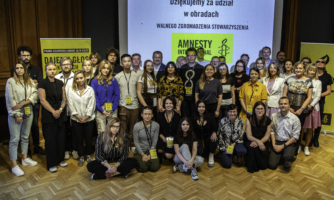 Duża grupa osób członkowskich Amnesty pozuje do wspólnego zdjęcia.