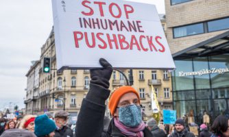 Osoba trzymająca transparent wzywający do zaprzestania pushbacków na granicy.