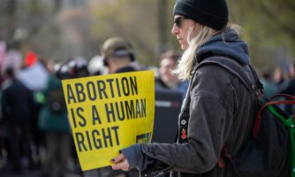 Kobieta na proteście trzymająca kartkę z hasłem proaborcyjnym.