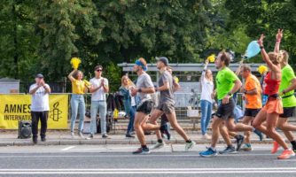 Uczestnicy biegu mijają punkt kibicowania Amnesty International.
