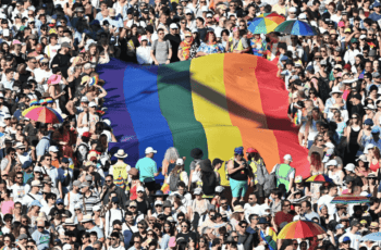 Tłum osób na marszu równości w Budapeszcie, w centrum duża tęczowa flaga.