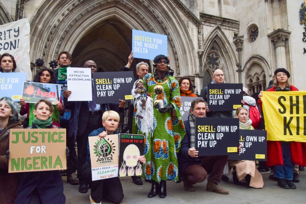 Grupa osób z transparentami protestuje przed londyńskim sądem.