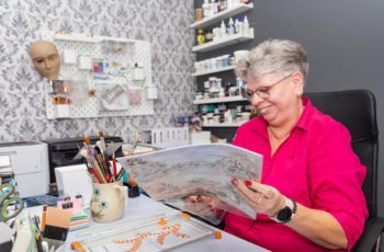 Uśmiechnięta kobieta w pracowni plastycznej.