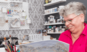 Uśmiechnięta kobieta w pracowni plastycznej.