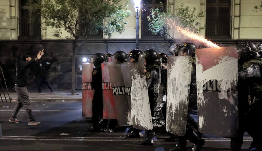 Mężczyzna stojący naprzeciw grupy uzbrojonych policjantów.