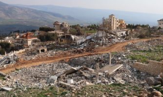 Widok na drogę i budynki po bombardowaniu, w tle góry.